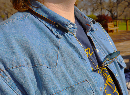 Person wearing a blue denim jacket with sunglasses on top, outdoors.