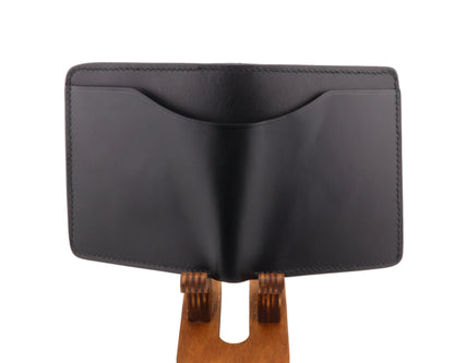 Black bifold wallet with money slot on a wooden stand against a white background