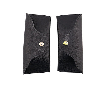 Two black leather cases with gold and silver buttons on a white background