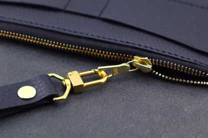 Close-up of a black bag with a gold zipper pull and strap.