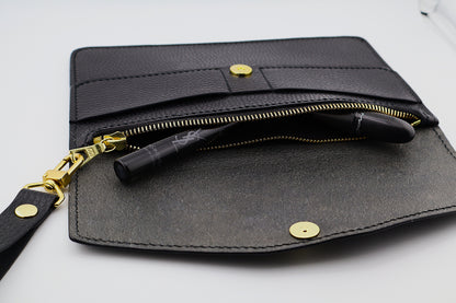 Black leather clutch with gold accents on a white background