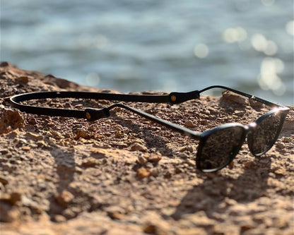 Sunglasses on a rock with water in the background